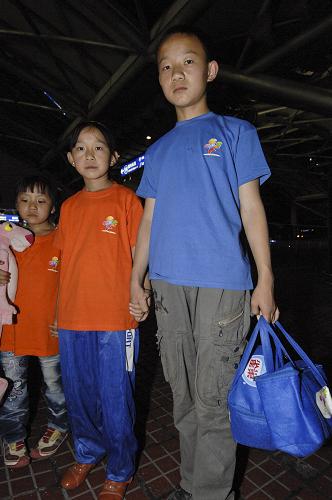 8月26日晚,13歲的尙海旺(右一)和11歲的尚海嬌(右二)是一對在甘肅舟曲泥石流中失去父母的兄妹,抵京后兩個人總是習慣手拉手走在一起。新華社發(fā)(張宇 攝)