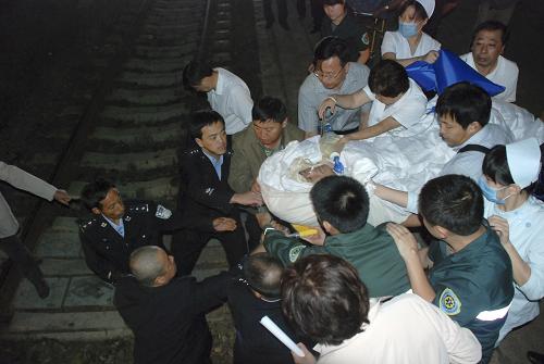 8月27日凌晨,工作人員將伊春空難傷員抬過鐵路路基,準(zhǔn)備送上專列。新華社發(fā)(劉宇 攝)