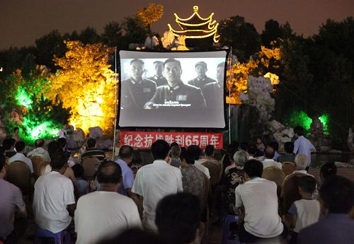 8月29日晚上,在江蘇宜興宜園廣場(chǎng),觀眾們?cè)谛蕾p抗戰(zhàn)電影《喋血孤城》。新華社發(fā)(丁煥新 攝)