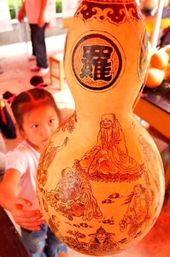 9月12日,聊城葫蘆文化節(jié)上展出的古畫工藝葫蘆吸引了一名女孩的目光。新華社發(fā)(張憲舉 攝)
