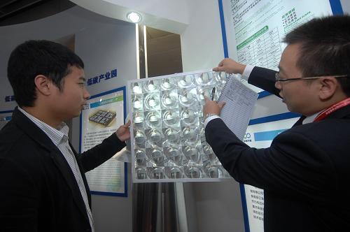 10月14日,參展商(右)向客戶介紹利用自然光發(fā)電的照明裝置。新華社記者 黃宗治 攝