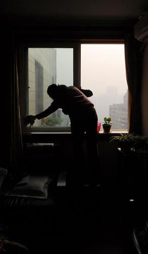 12月20日,在上海膠州路失火大樓相鄰的一幢大樓內(nèi),回搬的居民在房間里擦玻璃。新華社發(fā)