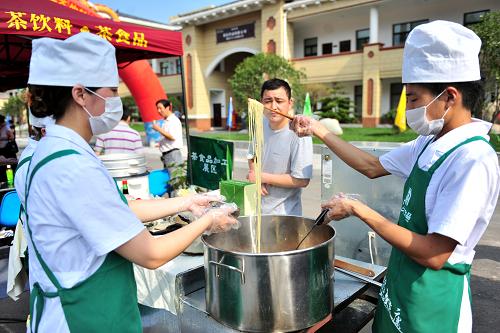 7月3日, 湖北宜昌市夷陵經(jīng)濟(jì)開發(fā)區(qū)茶業(yè)高新科技工業(yè)園,工作人員在茶食品加工展區(qū)煮茶面條。新華社發(fā)(張國榮 攝)