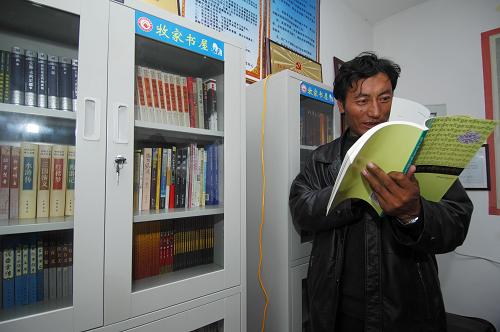 8月4日,瑪查理移民村村長尼瑪在村中的“牧家書屋”里翻閱藏文書。新華社記者 吳光于 攝