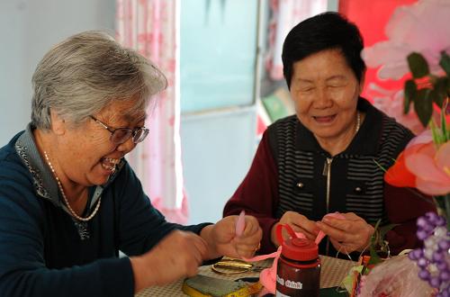 在烏魯木齊市水磨溝區(qū)長(zhǎng)青四隊(duì)南湖馨苑小區(qū)的居家托老所內(nèi),翟秀云老人(左)和王傳梅老人正在制作手工藝編織花卉(9月23日攝)。新華社記者 王菲 攝