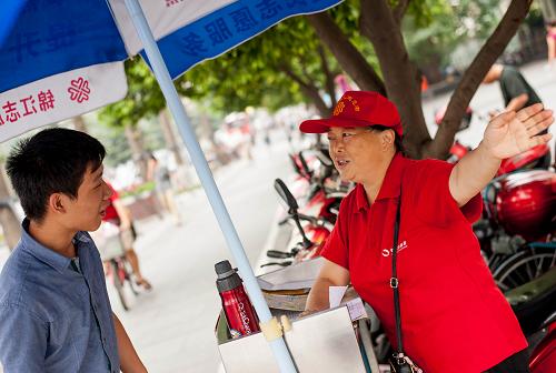 8月28日,55歲的志愿者徐麗華(右)在四川成都人民南路二段與濱江路交叉口的志愿者服務(wù)站為人指路。新華社發(fā)(李華梁 攝)