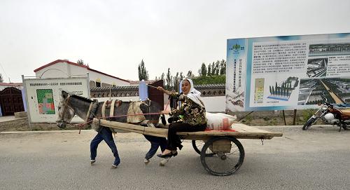 7月6日,新疆策勒縣一維吾爾族農(nóng)民趕著毛驢車從新建的“富民安居”試點(diǎn)區(qū)前經(jīng)過(guò)。在對(duì)口支援省市天津市的全力援助下,新疆策勒縣以大計(jì)劃、巧安排、細(xì)算賬和“一村一策”、“一戶一計(jì)”的規(guī)劃,加快“富民安居”試點(diǎn)項(xiàng)目建設(shè)。在建設(shè)安居工程同時(shí),為各族農(nóng)牧民在庭院中興建牲畜棚圈、蔬菜大棚和特色果園等設(shè)施,加快當(dāng)?shù)馗髯遛r(nóng)牧民富民安居步伐。新華社記者 沈橋 攝
