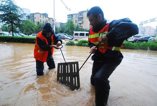 7月14日,在九江市廬山區(qū)十里大道,九江市政公司的工作人員打開雨水井蓋,加快積水排放速度。自13日中午開始,江西九江市區(qū)遭受暴雨襲擊,據(jù)江西省氣象部門發(fā)布的信息,7月13日12時至14日12時,江西九江市區(qū)的累計降雨量達到106毫米,部分地區(qū)內(nèi)澇嚴(yán)重,給交通和市民生活帶來不便。新華社發(fā)(胡國林 攝)