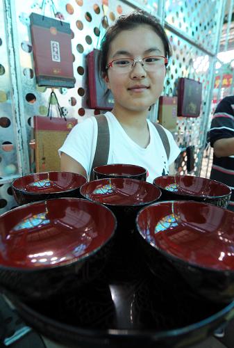7月19日,在上海世博園寶鋼大舞臺,湯天愛被精美考究的漆器碗具吸引。 今年16歲的江蘇姑娘湯天愛來到世博園參觀的第一站,就是上海寶鋼大舞臺傳習(xí)區(qū)。在這里,來自湖北的十多種民間傳統(tǒng)手工技藝展示讓小姑娘看得眼花繚亂,興奮不已。“沒想到,民間的手工技藝這么神奇、別致和復(fù)雜多樣,不來世博園,我還真不曉得湖北居然有這么多的傳統(tǒng)絕技!” 在2010年上海世博會期間,來自“千湖之省”荊楚之地的工作人員展示了楚式漆器制作、土家織錦、鉛錫刻鏤、大布傳統(tǒng)紡織、皮影戲及其雕鏤藝術(shù)等12種國家級、省級非物質(zhì)文化遺產(chǎn)項(xiàng)目。 在城市長大的湯天愛很少能看到這些民間手工技藝展示。這次在活動現(xiàn)場,傳承藝人各顯神通,技法嫻熟,讓湯天愛大開眼界。做一雙漆器筷子需要上百道嚴(yán)格而復(fù)雜的工序;古代青銅藝術(shù)在傳承老藝人的展示中神奇再現(xiàn);幾十種雕刻刀并用,在牛皮上雕刻出各種“影人”。民間“絕活”精、巧、奇、特,不一而足。 參觀結(jié)束后,湯天愛興猶未盡,她有一個愿望:“要是能把省區(qū)市的民間手工絕技集中起來,在全國各地巡展,那該多好?。∥覀冇胸?zé)任保護(hù)好民間傳統(tǒng)手工技藝,不能讓它們失傳。”新華社記者 侯德強(qiáng) 攝