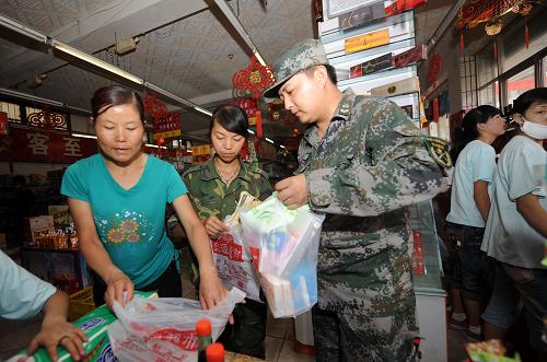8月11日,參與救援的解放軍在宏源超市職工選購生活用品。 位于舟曲縣政府門前的宏源超市8月10日正式恢復(fù)營業(yè),這是發(fā)生泥石流災(zāi)害以來舟曲縣城重新開張的第一家超市。宏源超市擁有15個直營店,是舟曲縣城最大的連鎖零售商店。在泥石流災(zāi)害中,宏源超市有7名職工全家遇難,目前堅持上班的職工中也有多人家里有親人失蹤或遇難。新華社記者 聶建江 攝
