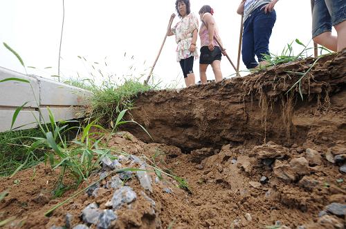 8月11日,幾名村民站在雙井控導(dǎo)工程壩面塌陷處,對(duì)工程質(zhì)量產(chǎn)生質(zhì)疑。由于近期多次出現(xiàn)降雨天氣,位于黃河北岸的河南省原陽(yáng)縣雙井村南黃河灘上的“雙井控導(dǎo)工程”壩面和堤坡出現(xiàn)80多處塌陷坑溝。記者沿這條新建的控導(dǎo)工程走過(guò),目擊了這些“累累傷痕”,當(dāng)?shù)氐拇迕駥?duì)壩上出現(xiàn)的安全隱患感到擔(dān)憂,并對(duì)工程質(zhì)量產(chǎn)生質(zhì)疑。一位村民說(shuō),新修的工程下場(chǎng)雨就沖成這個(gè)樣子,要是黃河出現(xiàn)大水豈不更可怕?據(jù)當(dāng)?shù)睾觿?wù)局專家介紹,這種塌陷的坑溝被稱為“水溝浪窩”,是由雨水沖擊形成的。該項(xiàng)目的主體工程已經(jīng)完工近一年,但還未通過(guò)驗(yàn)收。目前,有關(guān)部門(mén)已對(duì)此事展開(kāi)調(diào)查,當(dāng)?shù)睾觿?wù)局對(duì)出現(xiàn)的問(wèn)題開(kāi)始用土方進(jìn)行填補(bǔ)。近期黃河中游還將出現(xiàn)強(qiáng)降雨,黃河防洪將面臨比較嚴(yán)峻的形勢(shì)。新華社記者 趙鵬 攝