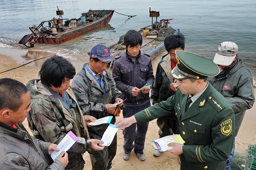 10月26日,秦皇島市黃莊邊防派出所民警李濤(右下)在轄區(qū)漁港走訪。河北省公安邊防總隊官兵在黃、渤海捕撈期不斷加大巡邏力度,對易發(fā)事故海域和漁港重點監(jiān)控,向作業(yè)人員宣傳相關(guān)法律知識,從嚴(yán)查處無證船舶,及時化解各類矛盾糾紛,積極打造和諧海域。新華社記者 楊世堯 攝