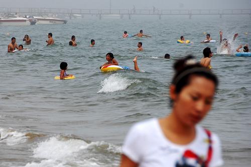在山東省蓬萊市海濱,游客在海水里暢游(7月13日攝)。國家海洋局北海分局和農(nóng)業(yè)部黃渤海區(qū)漁業(yè)生態(tài)環(huán)境監(jiān)測中心出具的最新檢測結(jié)果表明,中海油蓬萊19-3油田溢油事故發(fā)生后,已經(jīng)造成周邊3400平方公里海域由第一類水質(zhì)下降為第三、四類水質(zhì),這一污染外緣線尚未達到油田周邊山東、河北、天津等地管轄的近岸12海里(約22公里)海域,距離較近的山東省長島縣近岸海域水質(zhì)石油類含量尚未超標(biāo)。新華社記者 郭緒雷 攝