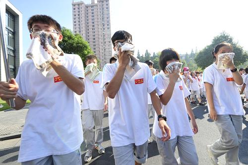 9月15日,學生在演習中用毛巾捂住口鼻前往應(yīng)急疏散區(qū)域集合。當日下午15時,浙江省暨杭州市城市應(yīng)急應(yīng)戰(zhàn)救援和跨區(qū)域支援研究性演習(代號浙江“金盾-11”)在杭州西湖區(qū)、臨安市等五個點同步舉行。來自江蘇、上海和浙江杭州、嘉興、湖州、紹興四市的1.5萬多人參加了演習。新華社發(fā)(李忠 攝)