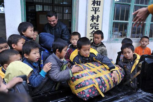 在廣西大化瑤族自治縣六也鄉(xiāng)和平村小學,孩子們接到愛心人士送來的衣物(12月20日攝)。大化瑤族自治縣是國家新時期扶貧開發(fā)重點縣。地處大石山區(qū)的廣西大化瑤族自治縣六也鄉(xiāng)和平村小學,只有1至4個年級。全校158名學生中有129名學生住校。隨著氣溫的降低,大部分學生還只是穿著涼鞋,在露天吃飯,用冷水洗碗。但是,國家營養(yǎng)午餐計劃、愛心人士無私的幫扶,讓孩子們在冬天感受到了溫暖。新華社記者 周華 攝