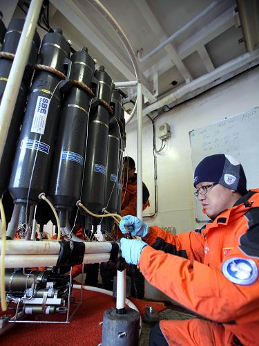 1月31日,考察隊(duì)隊(duì)員將玫瑰采水器采集上來(lái)的海水灌裝到采樣瓶里。新華社記者 徐硙 攝