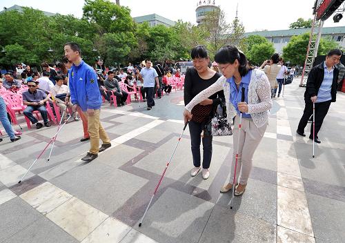 5月14日,在寧夏銀川市玉皇閣廣場上,銀川市殘疾人聯(lián)合會的工作人員幫助引導盲人使用盲杖進行定向行走。新華社記者 彭昭之 攝