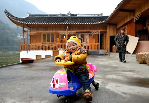 這是2014年1月12日,湖北省宣恩縣水田壩村農(nóng)民趙啟新(右后)帶著孫子在裝修一新的吊腳樓前玩耍。2014年中央一號(hào)文件指出,加快編制村莊規(guī)劃,推行以獎(jiǎng)促治政策,以治理垃圾、污水為重點(diǎn),改善村莊人居環(huán)境。新華社發(fā)(宋文 攝)