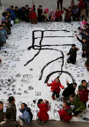 在安徽省馬鞍山市含山縣的孩子們展示他們和老師共同創(chuàng)作的《巨“馬”鬧春》書法作品(2014年1月20日攝)。 新華社發(fā)(程千俊 攝)