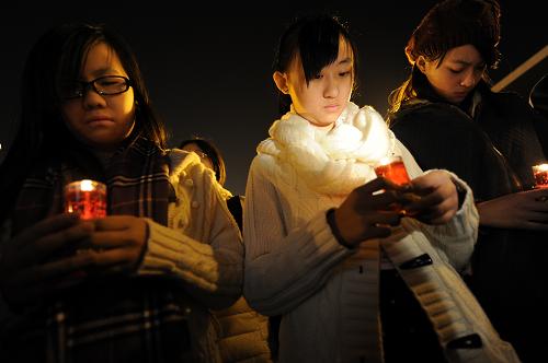 12月12日,來(lái)自中國(guó)香港的學(xué)生代表手捧紅燭為南京大屠殺遇難同胞守靈。新華社記者 韓瑜慶 攝