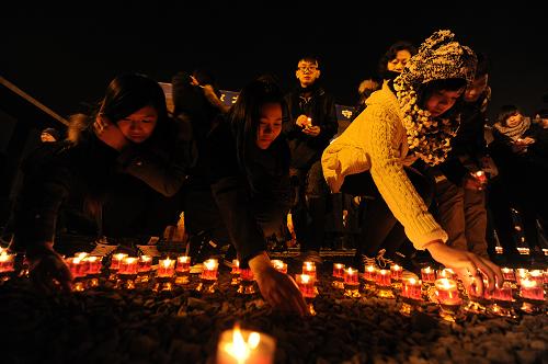 12月12日,來(lái)自中國(guó)香港的學(xué)生代表將點(diǎn)燃的紅燭放置在紀(jì)念館祭場(chǎng)的地面上。新華社記者 韓瑜慶 攝