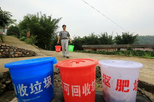 6月4日,在廣西柳州市融安縣大將鎮(zhèn)大潭屯,一名村民將分類好的垃圾送往收集點(diǎn)。新華社發(fā)(譚凱興 攝)
