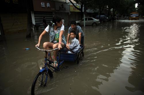 10月10日,在余姚市區(qū)一條積水道路上,人們涉水通行。新華社記者 韓傳號 攝