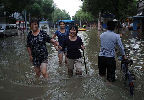 10月10日,在余姚市區(qū)一條積水道路上,人們涉水通行。新華社記者 韓傳號 攝