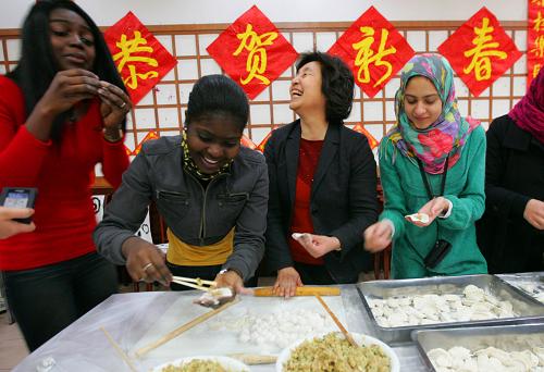 2月13日,來自海地的學(xué)生伊娜(左一)和莎洛敏(左二)和老師同學(xué)一起包餃子。新華社發(fā)