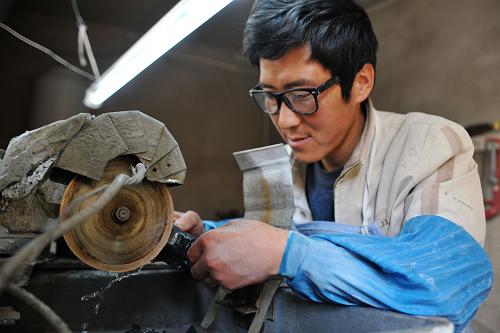 4月17日,在甘肅省武山縣車川村,村民包田紅在自己家里制作鴛鴦玉的夜光杯。新華社記者 陳斌 攝