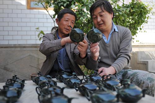 4月17日,在甘肅省武山縣車川村,村民車紅斌(右)和同伴一起檢查玉壺成品。新華社記者 陳斌 攝