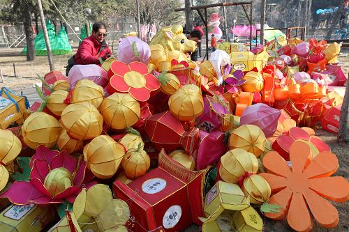 2014年1月1日,在棗莊市人民公園,民間藝人在挑選往年花燈會未損壞的花燈重復(fù)使用。新華社發(fā)(吉喆 攝)