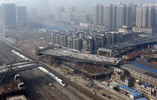 1月14日,湖北武漢姑嫂樹跨鐵路立交橋箱梁在進行高空轉(zhuǎn)體。當(dāng)日,跨越京廣等鐵路線的湖北武漢姑嫂樹公跨鐵立交橋箱梁成功實現(xiàn)空中轉(zhuǎn)體。該混凝土箱梁重達17300多噸,為目前我國最重的單個轉(zhuǎn)體建筑。整個箱梁在離地面10多米高處,通過電腦控制的千斤頂讓其空中轉(zhuǎn)體,跨越鐵路線后與另一側(cè)的箱梁實現(xiàn)全橋合龍。姑嫂樹公跨鐵立交橋位于漢口火車站附近,是該市姑嫂樹快速路控制性工程,立交橋上跨京廣、武合、漢孝等鐵路,橋梁總長256米。施工現(xiàn)場地處交通繁忙的鬧市,需要跨越10多股鐵路線。為減少立交橋施工對鐵路帶來的影響,該橋采用轉(zhuǎn)體法施工,即橋梁先在順鐵路方向澆筑,再通過轉(zhuǎn)體裝置實現(xiàn)轉(zhuǎn)體,橫跨鐵路。新華社發(fā)