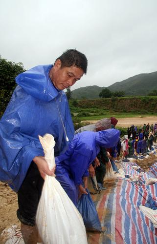 10月17日,在海南省陵水黎族自治縣,隆廣鎮(zhèn)基層村干部正在水庫壩體下方搬運(yùn)用來堵填管涌的沙袋。新華社記者 鄭瑋娜 攝