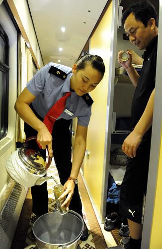 京藏車隊(duì)八組乘務(wù)員劉陽在北京開往拉薩的T27次列車上為旅客送水(7月17日攝)。新華社記者 唐召明 攝