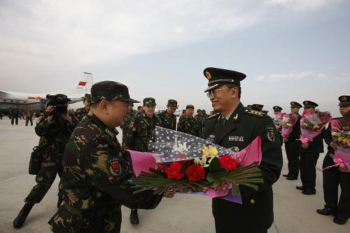 11月27日,在新疆喀什機(jī)場(chǎng),新疆軍區(qū)某部政委韓杰(前右)向返航的中方參演部隊(duì)回撤人員獻(xiàn)花。新華社記者 李翔 攝