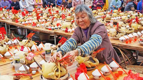 2月5日,在廣東湛江廉江市營(yíng)仔鎮(zhèn)云峽村的百雞宴上,一名老人給自家的雞夾紅包。當(dāng)日是農(nóng)歷正月十四,云峽村一帶的老百姓依習(xí)俗殺雞、設(shè)宴、祭祀,歡度當(dāng)?shù)貍鹘y(tǒng)“年例”。“年例”實(shí)際上是擴(kuò)大的元宵節(jié)、春節(jié)、廟會(huì),也包括祖先遷移落腳紀(jì)念日等在內(nèi)的綜合節(jié)日。明清朝代,“年例”已記入粵西的地方志,民國(guó)初年至解放初期都比較盛行,后來(lái)曾一度中斷,20世紀(jì)80年代以來(lái)逐漸恢復(fù)。新華社發(fā)(周龍 攝)