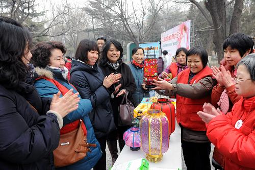 3月1日,受到巾幗志愿者熱情關(guān)懷的智障人士符志杰(右三)在活動中向來賓展示她制作的燈籠。新華社記者 何俊昌 攝