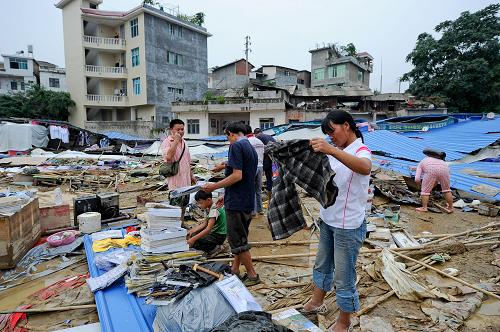 6月8日,望謨縣街頭一處被洪水沖毀的小商品市場外,幾名商販從廢墟中清理出衣物。 目前,貴州省、州、縣三級共籌集救災應急資金1400萬元下?lián)芙o望謨縣,截至7月7日16時,全省有解放軍、武警、消防、民兵、預備役人員1200人投入望謨抗洪搶險救災中。當?shù)厥転娜罕娬e極重建家園,恢復生活。 新華社記者 劉續(xù) 攝