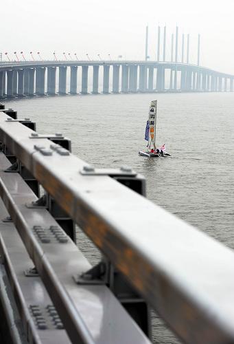世界最長跨海大橋——青島膠州灣大橋通車 6月30日,一艘帆船行駛在青島膠州灣大橋滄口航道橋附近。 當(dāng)日,青島膠州灣大橋正式通車,這是我國北方冰凍海域首座特大型橋梁集群工程,是國道主干線青島至蘭州高速公路的起點(diǎn)段,大橋全長36.48公里,是目前世界上已建成的最長的跨海大橋。大橋起于青島市東部高科園,跨越膠州灣,在黃島側(cè)與已建成的濟(jì)青南線順接,使青島、黃島和紅島實(shí)現(xiàn)“品”字形連接。大橋?yàn)殡p向六車道高速公路兼城市快速路八車道,設(shè)計(jì)行車速度80公里每小時(shí),橋梁寬度35米,設(shè)計(jì)基準(zhǔn)期100年。 新華社記者 李紫恒 攝