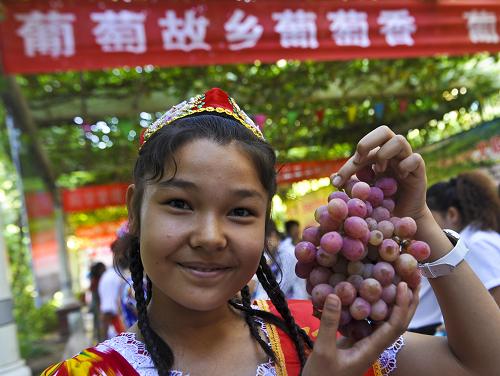 “葡萄王國”里品葡萄 在第22屆中國絲綢之路吐魯番葡萄節(jié)上,15歲的熱孜萬古麗在展示一串剛采摘的葡萄(8月20日攝)。 第22屆中國絲綢之路吐魯番葡萄節(jié)于8月20日在新疆吐魯番開幕。甜甜的葡萄吸引世界各地的游客慕名而來,當(dāng)?shù)剞r(nóng)民在收獲葡萄的同時,品嘗著葡萄帶來的“甜蜜”。目前,吐魯番地區(qū)葡萄種植面積超過45萬畝,總產(chǎn)量占全國的一成,農(nóng)民人均純收入的32%來源于葡萄及其加工業(yè)。 新華社記者 趙戈 攝