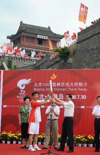 7月30日,在秦皇島火炬?zhèn)鬟f的起點老龍頭,第一棒火炬手郗恩庭(前左)接過火炬。當(dāng)日,北京奧運(yùn)圣火在河北省秦皇島市傳遞。 新華社記者鞏志宏攝
