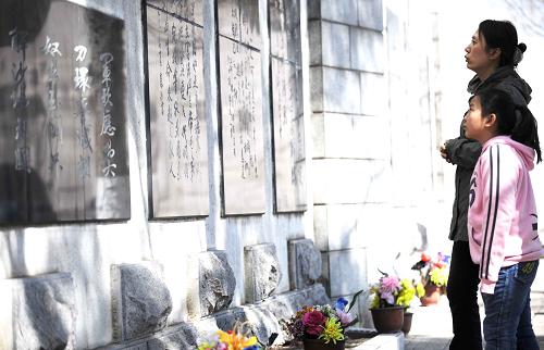 4月4日,一位家長領(lǐng)著孩子在哈爾濱烈士陵園內(nèi)瞻仰碑文。新華社記者 王建威 攝