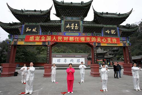 1月23日,在玉壘山廣場牌坊前排練的都江堰市某藝術(shù)團成員打出拱手拜年的手勢。新華社記者 鄭悅 攝