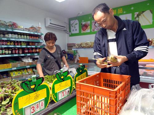 5月19日,一名殘疾人店員(右)在蘇州首家殘疾人農(nóng)產(chǎn)品平價直銷店內(nèi)整理蔬菜。新華社發(fā)(王建康 攝)