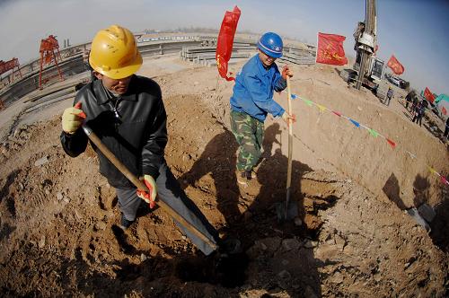 2月16日,工人們正在國道211線A8合同段的建設工地上鏟運砂石。新華社記者 彭昭之 攝