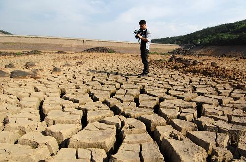6月1日,一位記者在拍攝湖州市長興縣周吳水庫干涸龜裂的庫底。新華社記者 鞠煥宗 攝