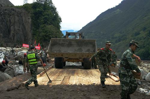 6月26日,丙中洛鄉(xiāng)雙拉村畢比利小組貢丙公路段,怒江公安邊防支隊搶險救援應(yīng)急分隊在鋪設(shè)木板,架設(shè)簡易便橋,目前已能保證車輛通行。此地原為石拱橋,在泥石流中被沖毀。6月23日下午5時10分至6時30分,云南省貢山獨龍族怒族自治縣境內(nèi)發(fā)生強降雨,多條河流暴發(fā)不同程度的山洪泥石流。暴雨導(dǎo)致丙中洛鄉(xiāng)雙拉村畢比利小組發(fā)生山洪泥石流災(zāi)害,250戶、500間民房受損,貢(山)—丙(中洛)公路中斷。災(zāi)害發(fā)生后,邊防、消防、民兵等400余名救災(zāi)人員全力投入搶險救援,被沖毀的貢山縣城至丙中洛鄉(xiāng)的公路于26日10時05分恢復(fù)通車。新華社發(fā)(茶志強 攝)