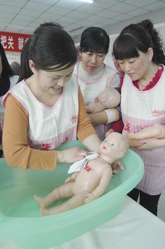 2月21日,在濟(jì)南陽光大姐家政服務(wù)培訓(xùn)中心,來自山東聊城的宓梅(左)在練習(xí)為新生兒洗澡。新華社發(fā)(張振祥攝)