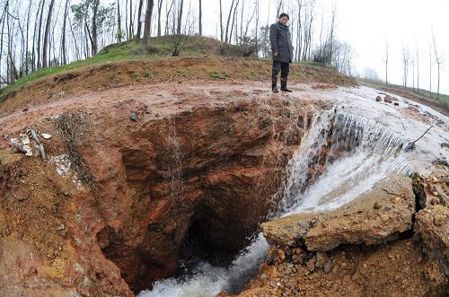 益陽市岳家橋鎮(zhèn)被截流的河水涌入塌陷形成的深坑(2月26日攝)。從2012年元月至2月24日,位于洞庭湖區(qū)的湖南省益陽市岳家橋鎮(zhèn)岳家橋、黃板橋等村發(fā)生大面積的巖溶塌陷地質(zhì)災(zāi)害,上千當?shù)卮迕竦纳a(chǎn)生活受到影響。記者從益陽市國土資源局了解到,目前整個岳家橋鎮(zhèn)共出現(xiàn)塌陷693處,其中農(nóng)田塌陷537處,河溪塌陷150處,水庫內(nèi)塌陷6處。全鎮(zhèn)因地面巖溶塌陷引起房屋開裂的有167戶,其中房屋受損特別嚴重的有34戶,受災(zāi)人口達1200多人;破壞河溪攔壩5座,水庫2座,影響農(nóng)田灌溉1萬多畝,致使泉交河支流河水斷流,沿河兩岸部分群眾生產(chǎn)生活陷入困境。新華社記者 龍弘濤 攝